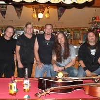 The band gathered around a pool table with guitars