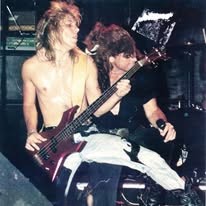 Shirtless bassist and guitarist on a small club stage in the late '80s