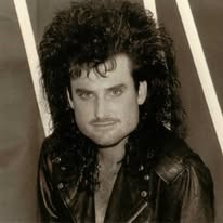 1980s portrait of a band member with big curly hair and a leather jacket